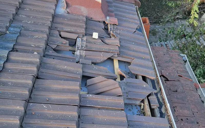 Versant de toiture aux tuiles brisées avant réparation