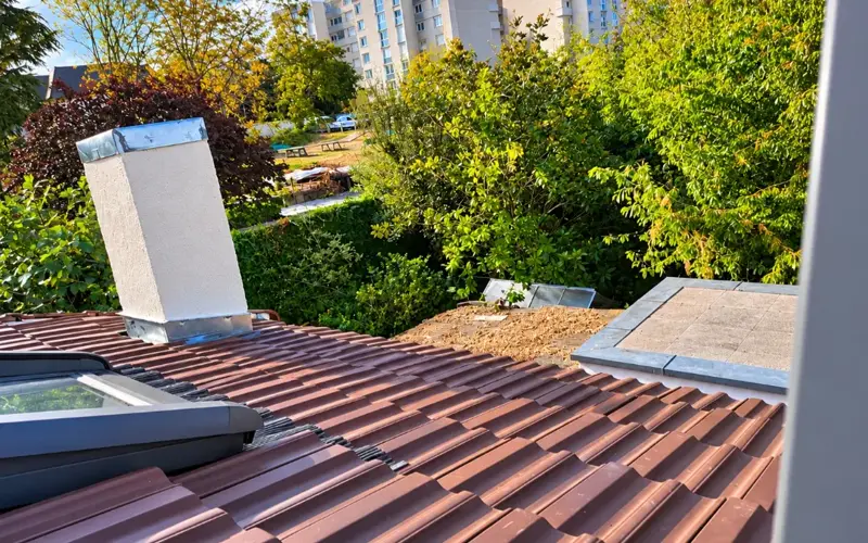 Souche de cheminée refaite et enduite au-dessus d'une toiture en tuiles